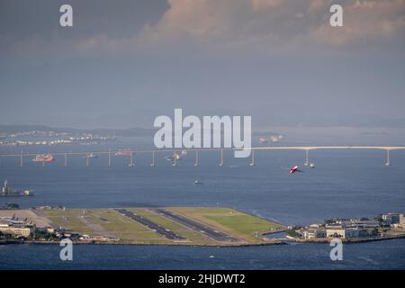 Brasile, Rio de Janeiro. Aereo che decade dalla pista all'aeroporto Santos Dumont nel centro della città. Guanabara Bay e Rio-Nitreoi ponte dietro. Giorno. Foto Stock