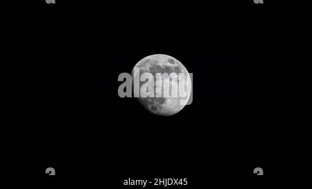Primo piano della luna ceretta - un giorno prima della luna piena - cattura di prima serata contro il cielo nero scuro. Stoccarda, Germania 22 gennaio 2022 Foto Stock