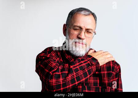 Ritratto di uomo maturo isolato su sfondo grigio che soffre di gravi dolori del corpo, chiudere gli occhi per alleviare il dolore Foto Stock