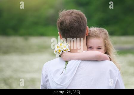 Padre e figlia nel grande prato di montagna camomilla. Scena emozionale, d'amore e di cura. Foto Stock