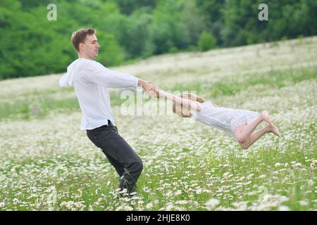 Felice padre giocare con la figlia in grande camomilla prato di montagna. Scena emozionale, d'amore e di cura. Foto Stock