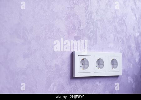 Presa a muro e parete viola. Dopo la riparazione. Profondità di campo poco profonda Foto Stock