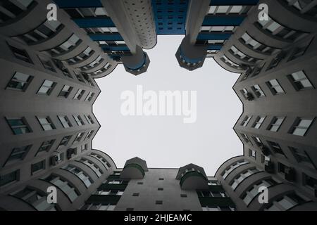 vista dal basso delle nuvole grigie nel cielo tra vecchia casa in mattoni nella grande città in inverno sera cortile-bene Foto Stock