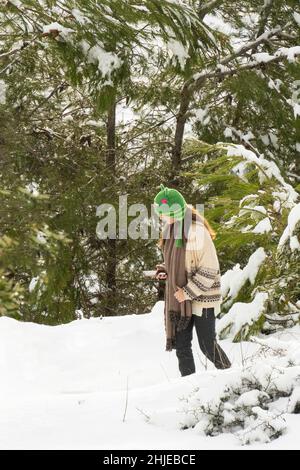 Mevasseret Zion, Israele - 27th gennaio 2022: Una ragazza adolescente che cammina in una foresta di pini nevosi, guardando il suo smartphone. Foto Stock