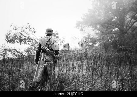 Unico Re-enactor vestito come il tedesco della Wehrmacht Soldato di fanteria nella guerra mondiale II a piedi in pattuglia attraverso la foresta di autunno. WWII WW2 volte. Foto in bianco e nero Foto Stock