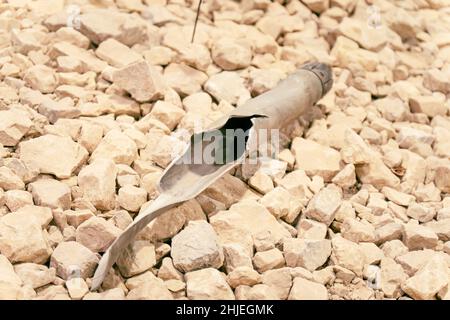 una conchiglia di artiglieria lacerata sul terreno di pietra. Foto Stock