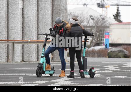 Una giovane coppia in vacanza a Reykjavík Islanda nel gennaio 2022 assumendo 2 scooter e nella piazza fuori dalla Cattedrale di Hallgrímskirkja Foto Stock