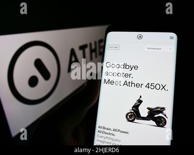 Persona che tiene smartphone con sito web della società indiana scooter ather Energy Pvt. Ltd. Su schermo con logo. Concentrarsi sul centro del display del telefono. Foto Stock