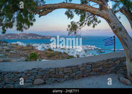 Vista elevata dei mulini di farina, città e bandiera greca all'alba, Mykonos Town, Mykonos, Isole Cicladi, Isole greche, Mar Egeo, Grecia, Europa Foto Stock