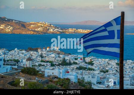 Vista elevata dei mulini di farina, città e bandiera greca all'alba, Mykonos Town, Mykonos, Isole Cicladi, Isole greche, Mar Egeo, Grecia, Europa Foto Stock