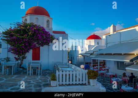 Vista della cappella a cupola rossa e ristorante nella città di Mykonos al tramonto, Mykonos, Isole Cicladi, Isole Greche, Mar Egeo, Grecia, Europa Foto Stock