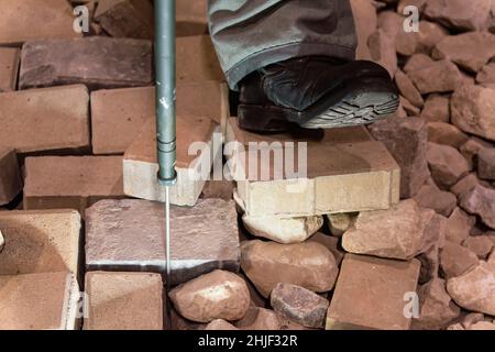 Un minesweeper cerca le miniere a terra con una sonda metallica Foto Stock