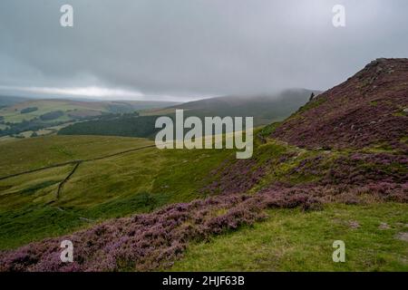 Vasto paesaggio delle colline del Peak District ricoperte di nuvole e nebbia, verde vista naturale della collina con macchie di erica e rocce. Moody punto di riferimento di Foto Stock