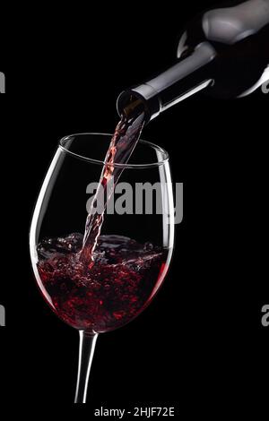 vino rosso versato in bicchiere da bottiglia isolato Foto Stock