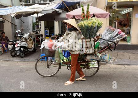 Un tradizionale venditore di fiori con la sua bicicletta per le strade del vecchio quartiere di Hanoi, Vietnam, Sud-Est asiatico Foto Stock