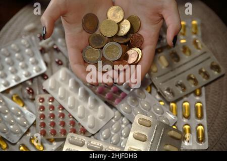 Monete in euro nelle mani femminili su molti blister di pillole, farmaci, compresse e capsule Foto Stock