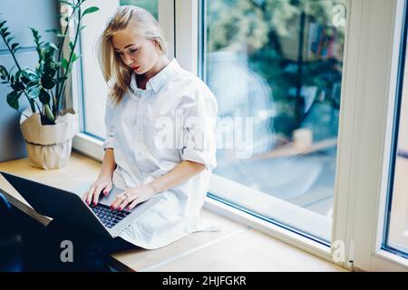 Dattilografia femminile seria sul laptop Foto Stock