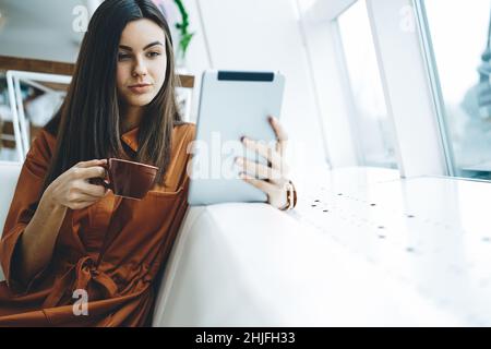 Donna che naviga su Internet sul tablet in salotto Foto Stock