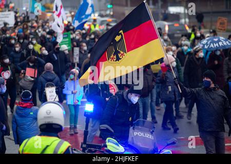 Friburgo, Germania. 29 gennaio 2022, bassa Sassonia, Osnabrück: I manifestanti camminano con una bandiera tedesca attraverso una strada cordonata dalla polizia.i partecipanti dimostrano contro la politica di Corona. Credit: dpa Picture Alliance/Alamy Live News Foto Stock