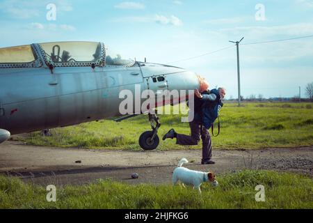 Un uomo di mezza età vicino a un vecchio piano sovietico abbandonato. Aereo sul campo del vecchio aeroporto. Foto Stock