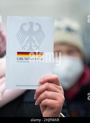 Friburgo, Germania. 29 gennaio 2022, bassa Sassonia, Osnabrück: Una copia della Legge fondamentale per la Repubblica federale di Germania dell'Agenzia federale per l'educazione civica è detenuta dal dimostratore. I partecipanti si dimostrano contrari alla politica di Corona. Credit: dpa Picture Alliance/Alamy Live News Foto Stock