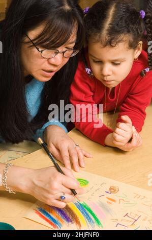 Preschool classe 4-5 anni insegnante femminile con ragazza che dice ad alta voce che cosa sta scrivendo per il bambino sul suo disegno Foto Stock