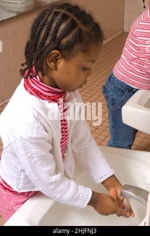 Istruzione Preschool classe età 4-5 ragazza lavaggio le proprie mani al lavandino in bagno Foto Stock