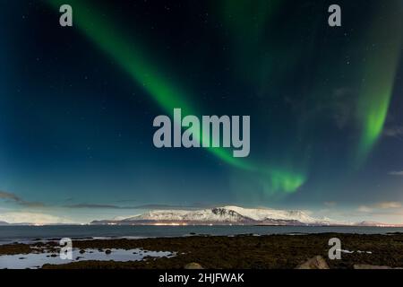 L'aurora boreale sopra il Monte Esja innevato nella capitale islandese, Reykjavic. Foto Stock