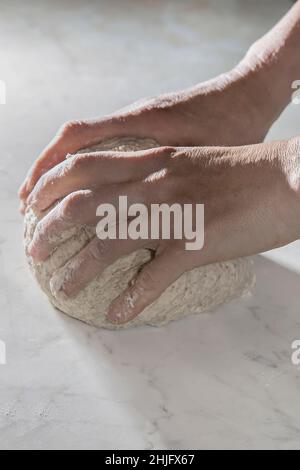 Preparazione del pane fatta in casa in Toscana con farina biologica su tavola bianca. Le mani delle donne preparano l'impasto del pane. Foto Stock