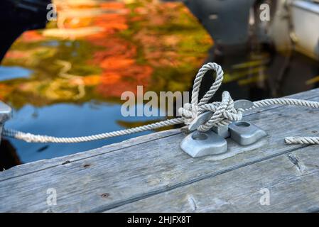 primo piano di una corda annodata ad una chiatta d'acciaio in un porticciolo in una giornata d'autunno soleggiata Foto Stock