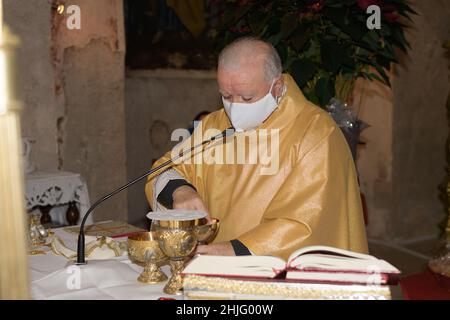 SAN PIETRO, ITALIA - DICEMBRE, 26, 2021. Prete maggiore che indossa un mazzo per il viso che prepara la celebrazione del sacramento dell'Eucaristia, tenendosi in mano Foto Stock