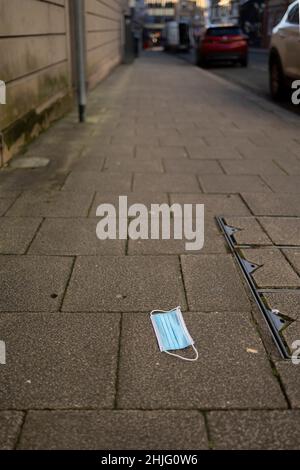 maschera medica scartata in modo errato sul marciapiede in un centro città nessuna gente ha selezionato fuoco Foto Stock