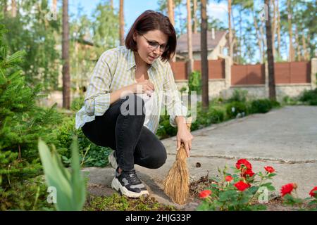 Donna che spazzava con una scopa nel cortile Foto Stock