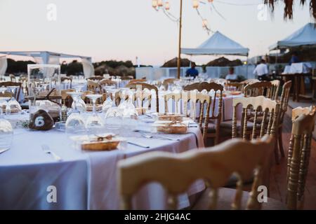 Elegante tavolo allestito per matrimoni in beige. Cena di nozze allestito vicino al mare, evento allestito Foto Stock