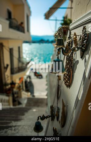 Le campane della porta sono vendute sulle strade di una piccola città sull'isola di Grecia, il mare è sullo sfondo. Paros, Grecia Foto Stock