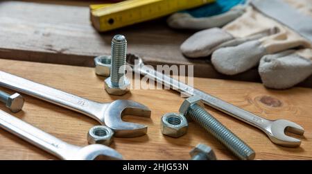 Chiave dado e vite su fondo in legno. Attrezzo manuale per riparazione e costruzione su tavolo da officina, vista da primo piano Foto Stock