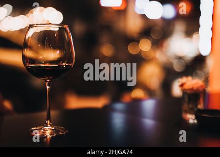 Vino rosso in calice contro le luci sfocate della sera Foto Stock