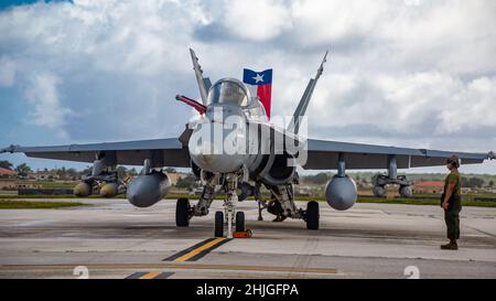 US Marine Corps Lance CPL. Lorenzo Nunez, un meccanico Powerline con Marine Fighter Attack Squadron 112, osserva che l'equipaggio esegue controlli pre-volo su un aereo F/A-18C Hornet presso la base dell'aeronautica Andersen, Guam, 25 gennaio 2022. I Marines con VMFA-112 stanno effettuando un addestramento a livello di unità presso la base dell'aeronautica di Andersen come parte di un programma di trasferimento di addestramento dell'aviazione. (STATI UNITI Foto del corpo marino di Sgt. Booker T. Thomas III) Foto Stock