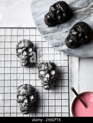 Una vista dall'alto di piccole torte di cioccolato a forma di cranio smaltate con glassa bianca Foto Stock