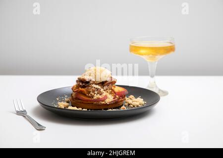 Cobbler alla pesca con panna coagulata e noci pecan candite Foto Stock