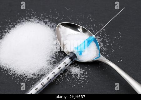 Siringa per iniezione di farmaco ed eroina cotta in un sacchetto su sfondo nero Foto Stock