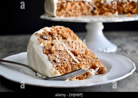 Fetta di torta di carote con glassa di formaggio cremoso su un piatto bianco con forchetta Foto Stock