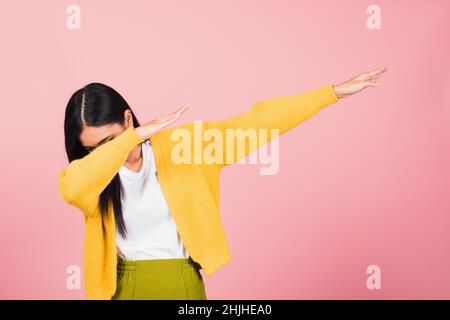 Asian felice ritratto bello cute giovane donna teen sorriso in piedi muoversi mostrando DAB danza contro gesto sollevare le mani braccia coprendo faccia isolata, s. Foto Stock