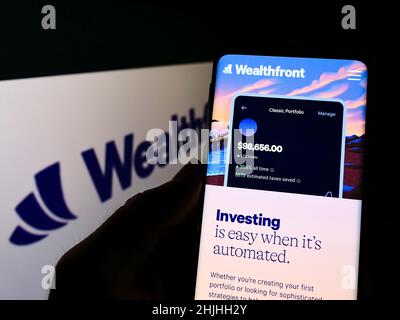 Persona che detiene il cellulare con il sito web della società FinTech USA Wealthfront Corporation sullo schermo di fronte al logo. Concentrarsi sul centro del display del telefono. Foto Stock