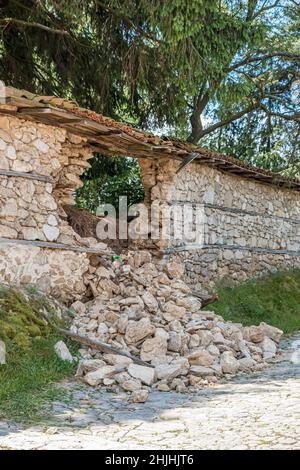 Parzialmente distrutto muro parte della pietra recinzione di una casa in un villaggio bulgaro. Foto Stock