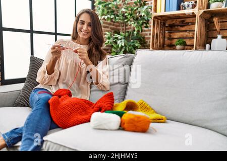 Giovane ispanica sorridente fidata tessendo in finisce a casa Foto Stock