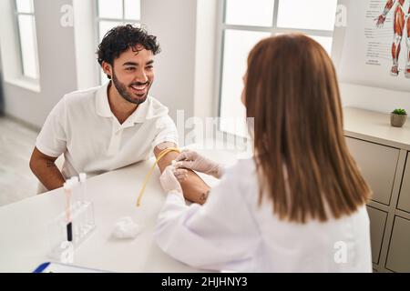 L'uomo e la donna che indossano l'uniforme del medico che hanno analisi del sangue in clinica Foto Stock