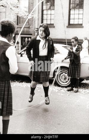 Le ragazze della scuola giocano il doppio salto olandese su una strada laterale a Brooklyn, New York all'inizio del 1980s. Foto Stock