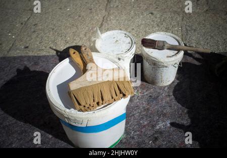 Il pittore pennelli sopra i secchi. Pavimento in pietra di granito protetto con coperta Foto Stock