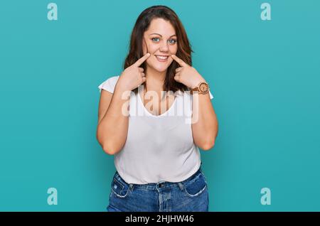 Giovane donna di più misura che indossa casual t shirt bianca sorridente con bocca aperta, le dita puntano e costringono il sorriso allegro Foto Stock